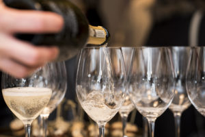 Close up photo of someone pouring a champagne into a glasses.